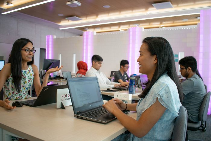 photo of two women at a table with laptops